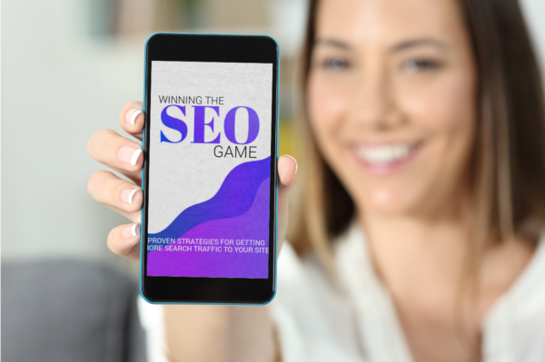 Image of a woman holding her mobile with a mockup of "Winning the SEO Game."| Purely Write