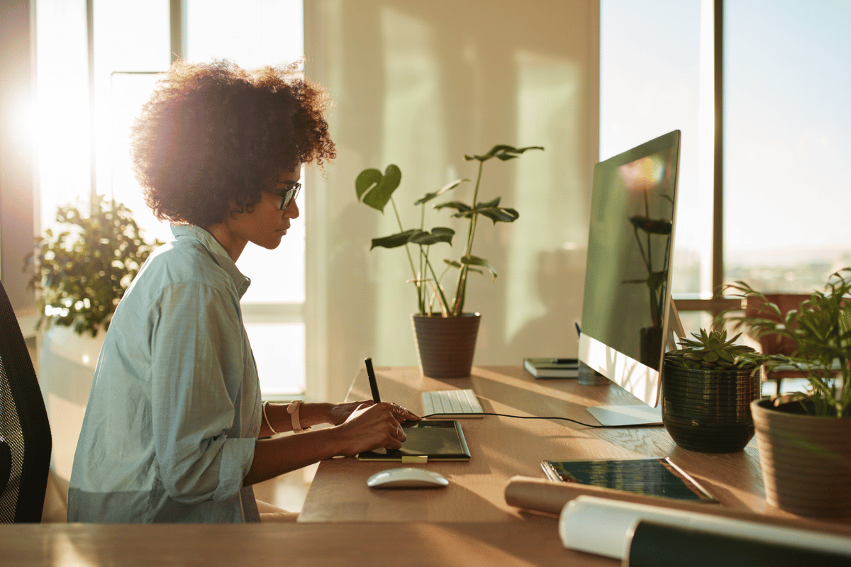 Image of a woman writing on her tablet at her desk.| Purely Write